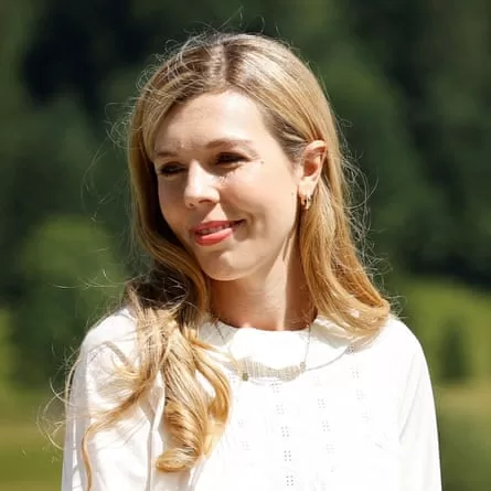 Head and shoulders of Carrie Johnson wearing a white summer outfit.